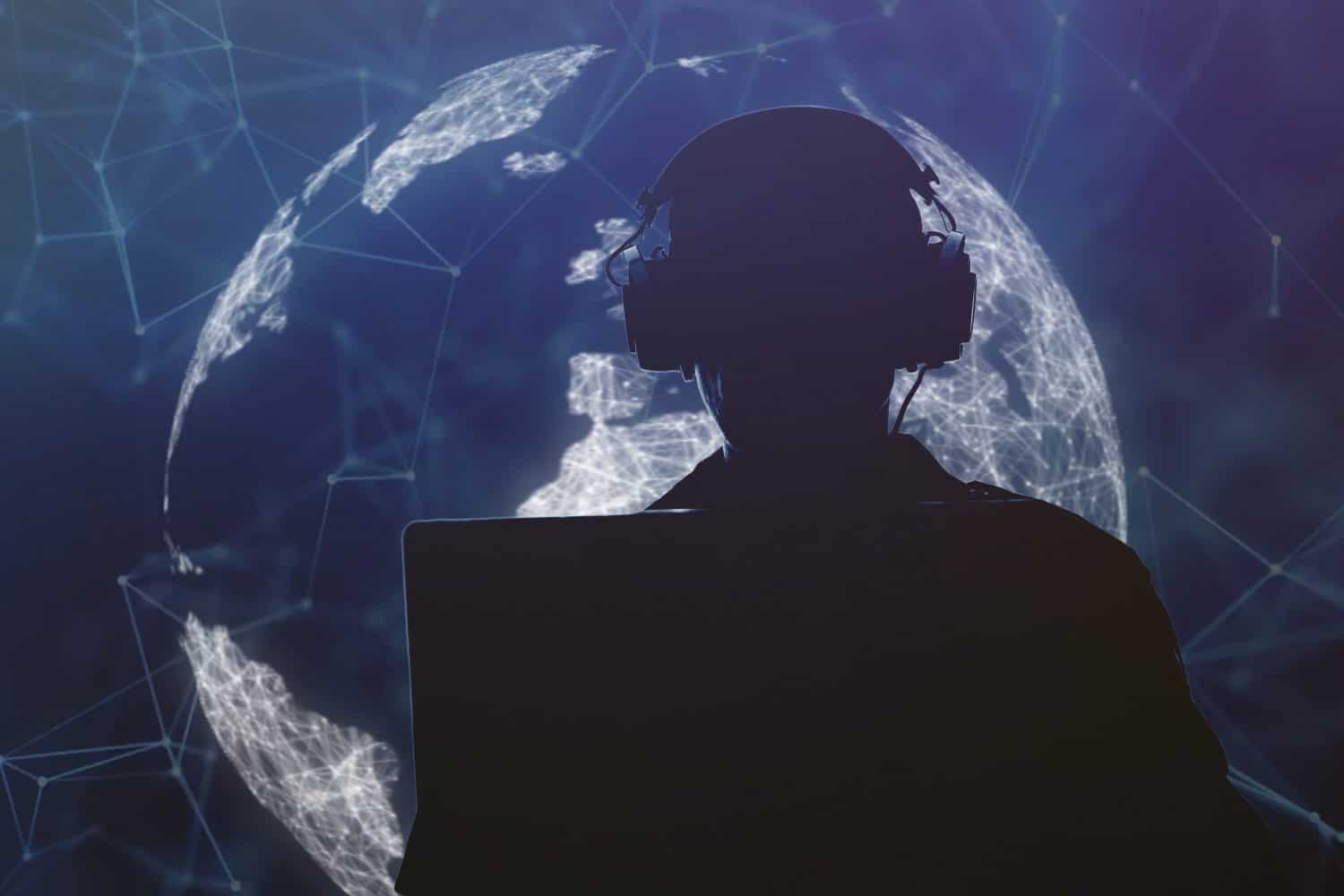 Silhouette of a military man in headphones at a laptop against the background of a digital globe of the earth, contour lighting. Concept: collection of confidential information, surveillance.