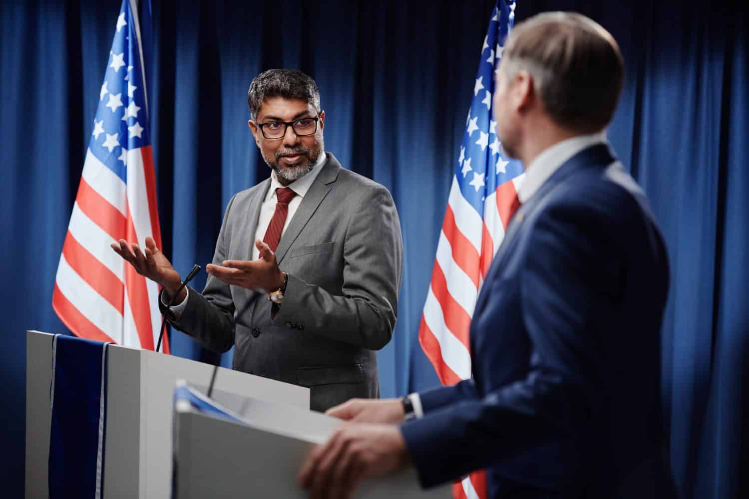 Confident mature multiethnic male politician in formalwear and eyeglasses looking at opponent during discussion of political issues