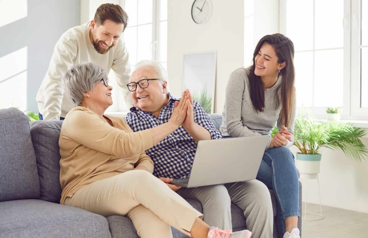 Happy family, aging old parents and adult children, two generations learn using laptop online home. Senior people, grown kids in loving kind affection, trust, family care, peace over generations