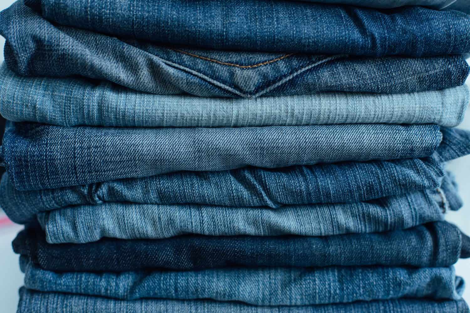 Stack of a stack of old jeans various shades of blue jeans. Denim jeans texture. Denim background texture for design. Canvas denim texture. Blue denim background.