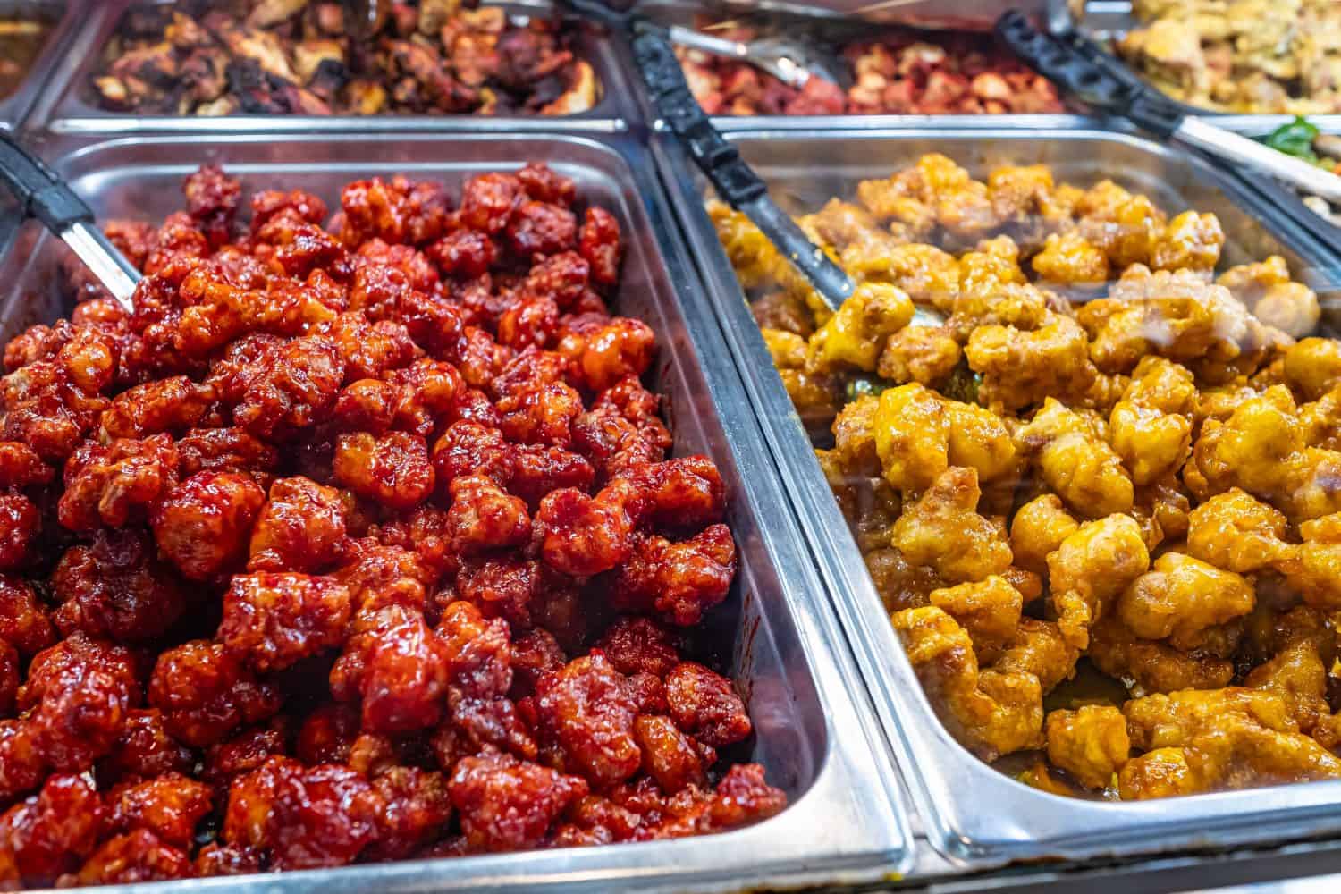 Hot food bar in supermarket. Showcase of a culinary shop. Closeup of Hot Bar food in trays inside local Store Foods Market. Supermarket Various of food. Assortment of appetizers.