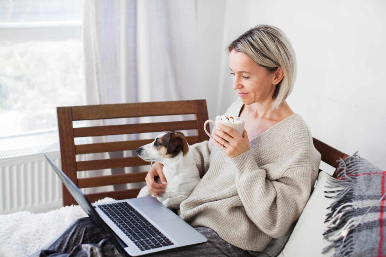 Happy middle aged woman using her laptop on the sofa at cozy home