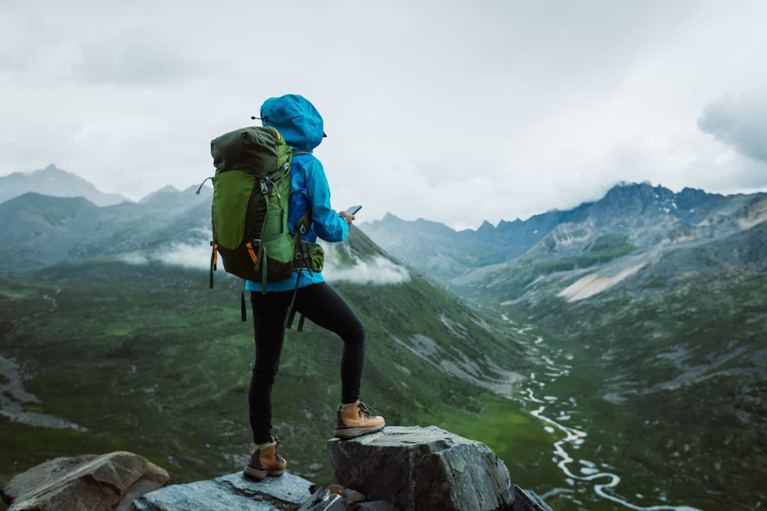 Hiking woman taking photo with smart phone on high altitude mountain top