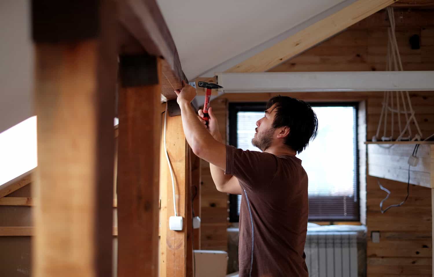 Man building a house and workimg with hammer and wood.