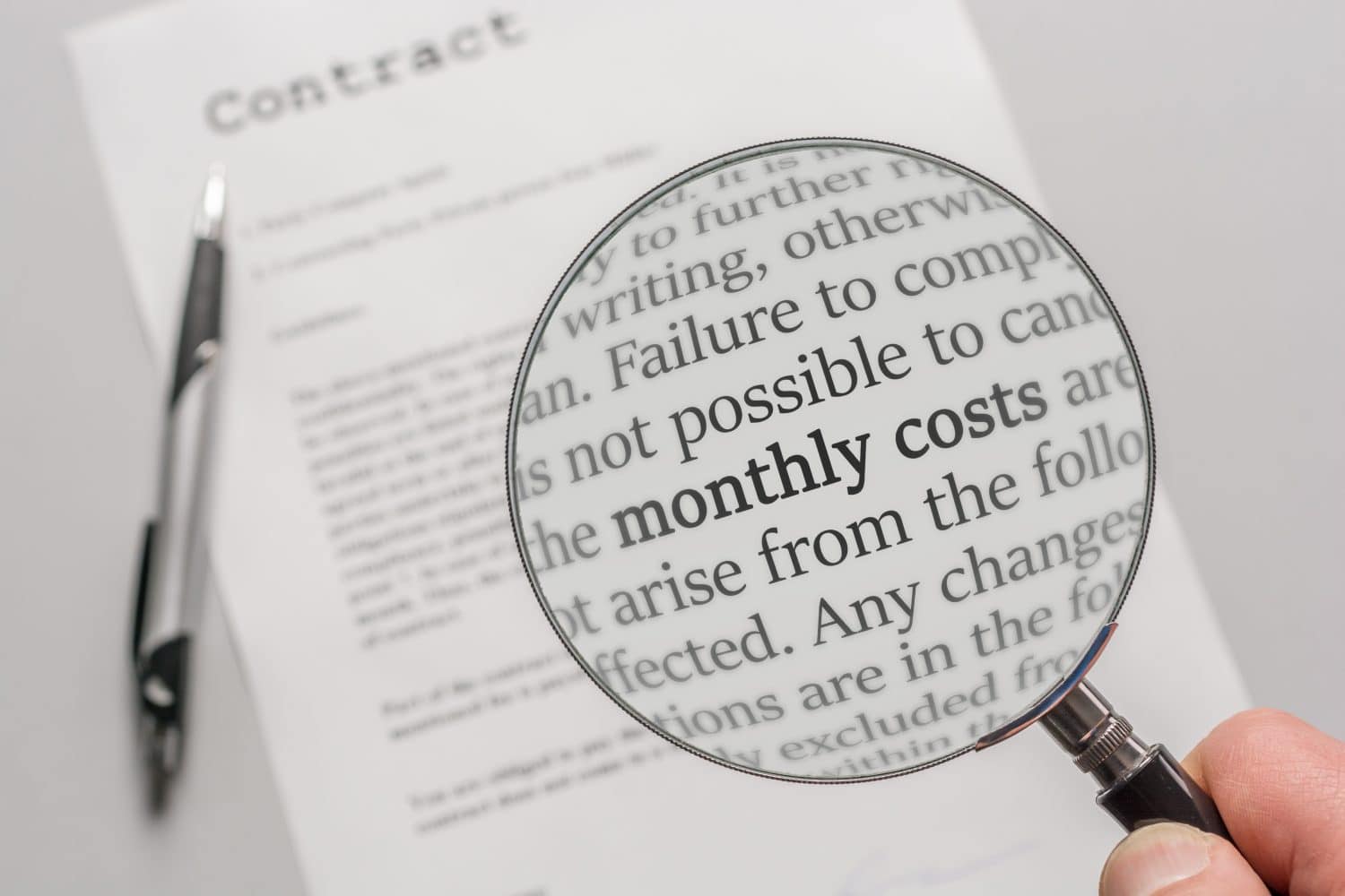 Contract is checked with a magnifying glass on the subject of monthly costs as a result of a contract