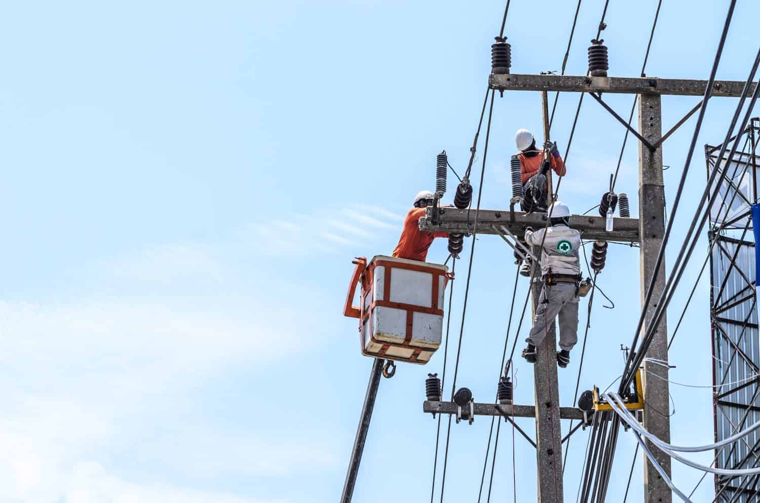 Electricians are climbing on electric poles to install and repair power lines.