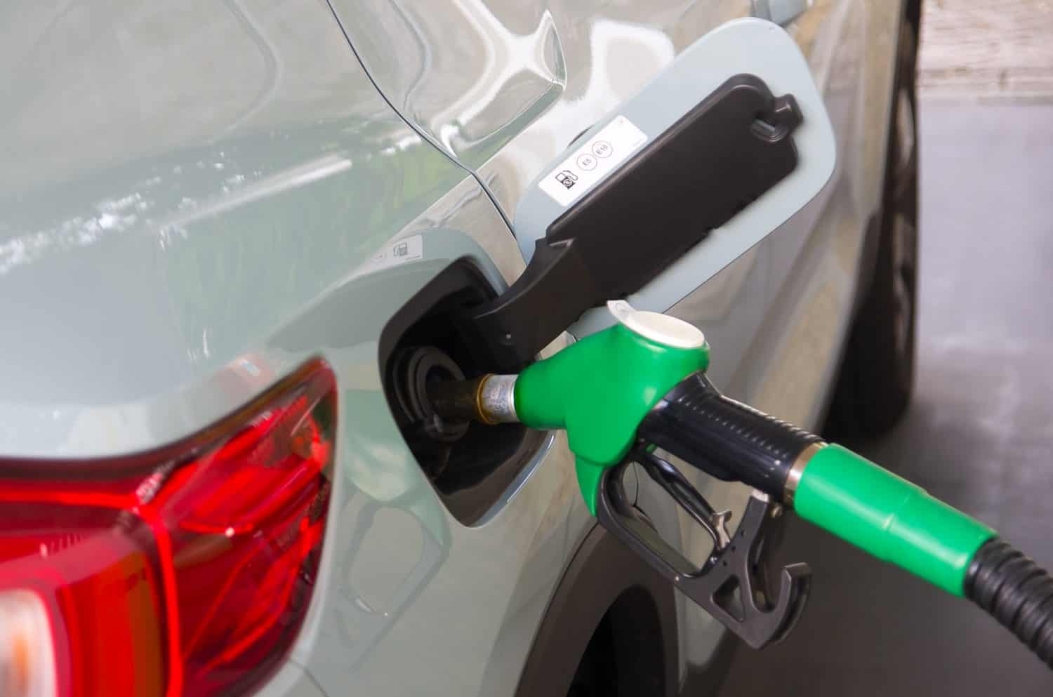 Close up of nozzle refueling azure blue car with gasoline