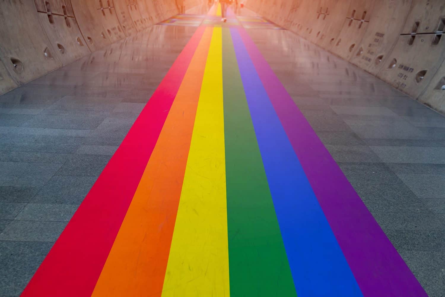 Gay pride rainbow colors or LGBT colors is in underground tunnel.Transport walkway by Tunnel Boring Machine for infrastructure subway with raw concrete segments wall.Light at the end of the tunnel.