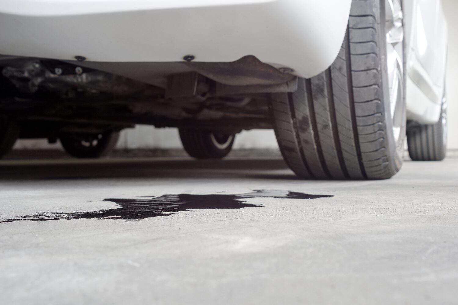 Selective focus of Engine oil stains of car Leaking under the car on blurred Car parked background.