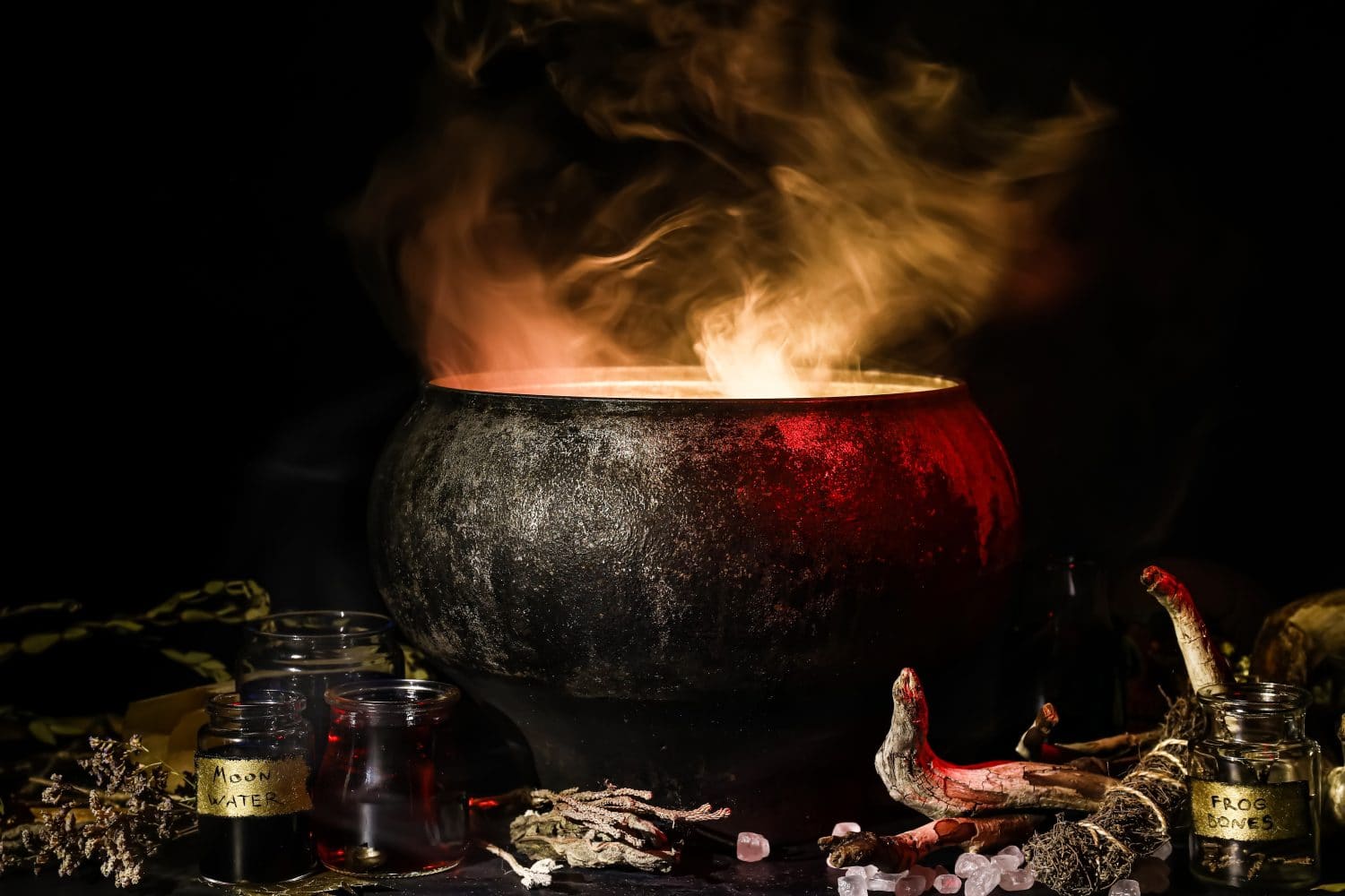 Witch&#039;s cauldron with potion and different magic attributes for ritual on dark background