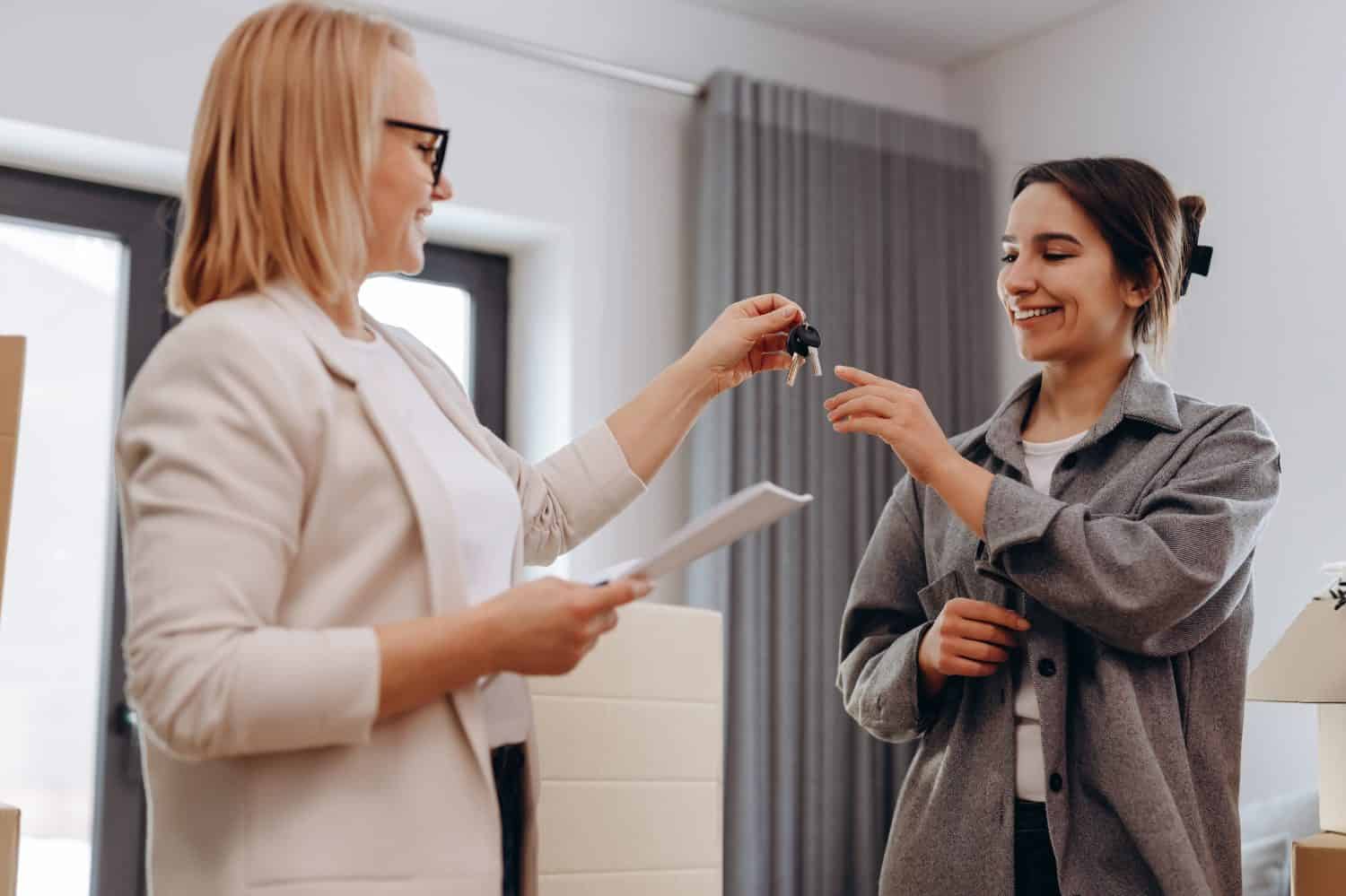 Close up young female real estate agent giving keys to happy buyer, congratulating with purchasing apartment. Millennial woman taking in leasing new house, accommodation tenancy rental service concept