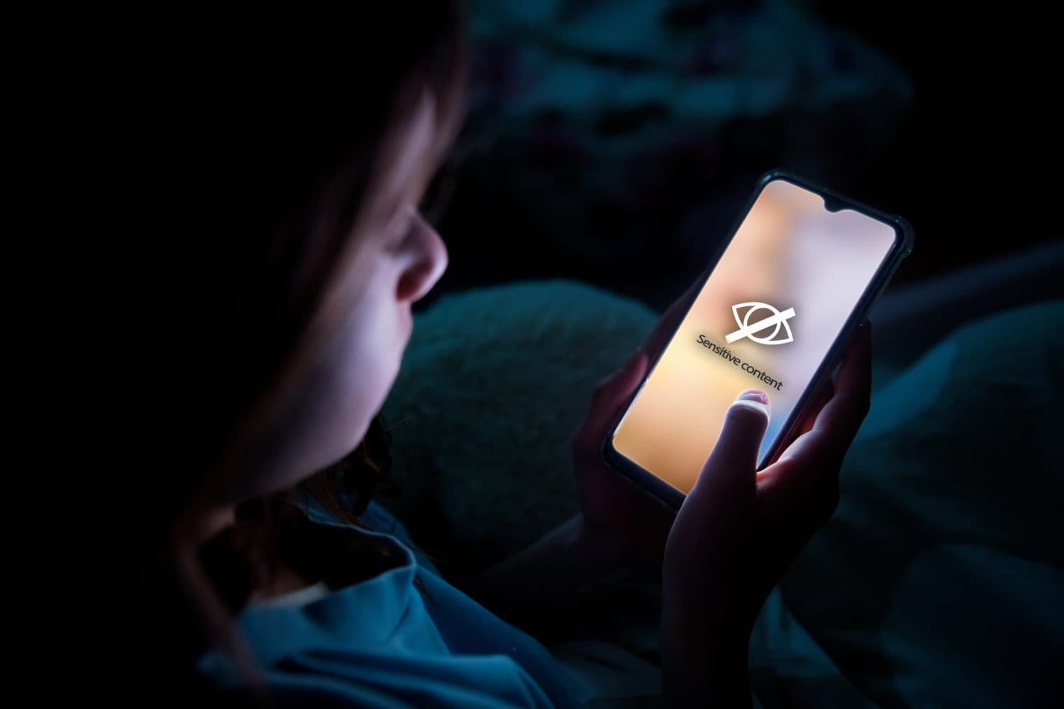 A child using smart phone lying in bed late at night, playing games. Children&#039;s screen addiction and parent control concept. Child&#039;s room at night. Sensitive content on screen