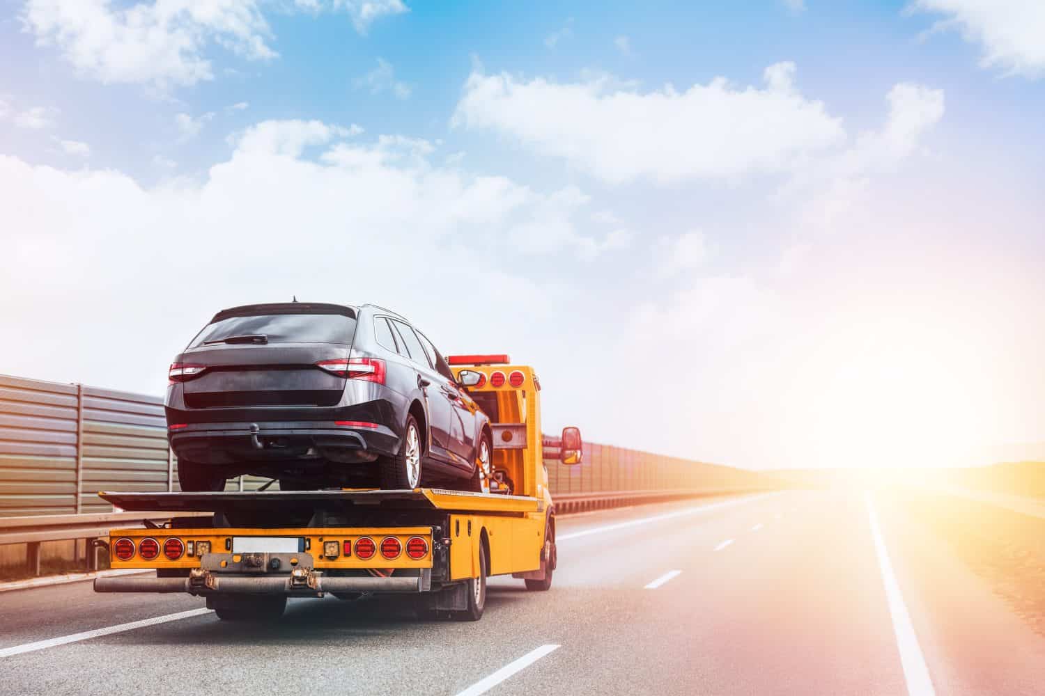 A tow truck on the public road. Tow truck with broken car on country road. Tow truck transporting car on the highway. Car service transportation concept.