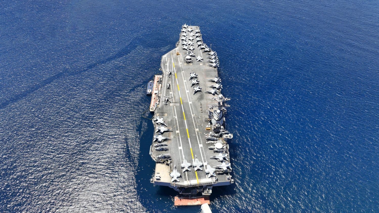 Aerial drone photo of USS Gerald R. Ford latest technology nuclear powered aircraft carrier anchored in deep blue open ocean sea