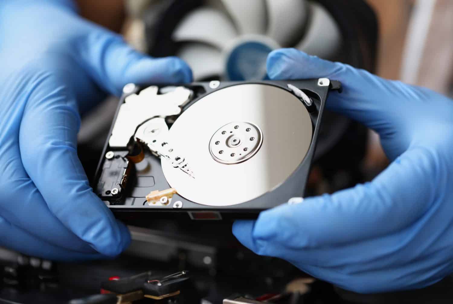 Gloved master holds computer hard drive. Computer equipment repair and maintenance concept