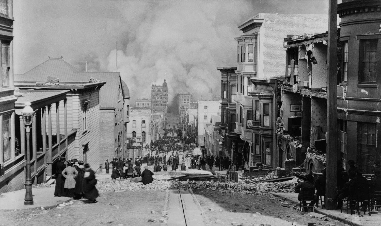 AFTER THE EARTH QUAKE, SAN FRANCISCO. Observers in chairs amid the debris on Sacramento Streetwatch the city burn. Photo by Arnold Genthe.