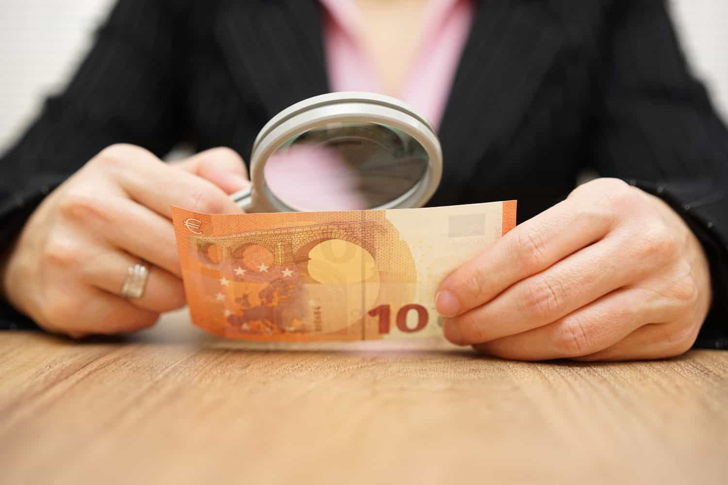 Businesswoman looking through a magnifying glass money. fraud concept