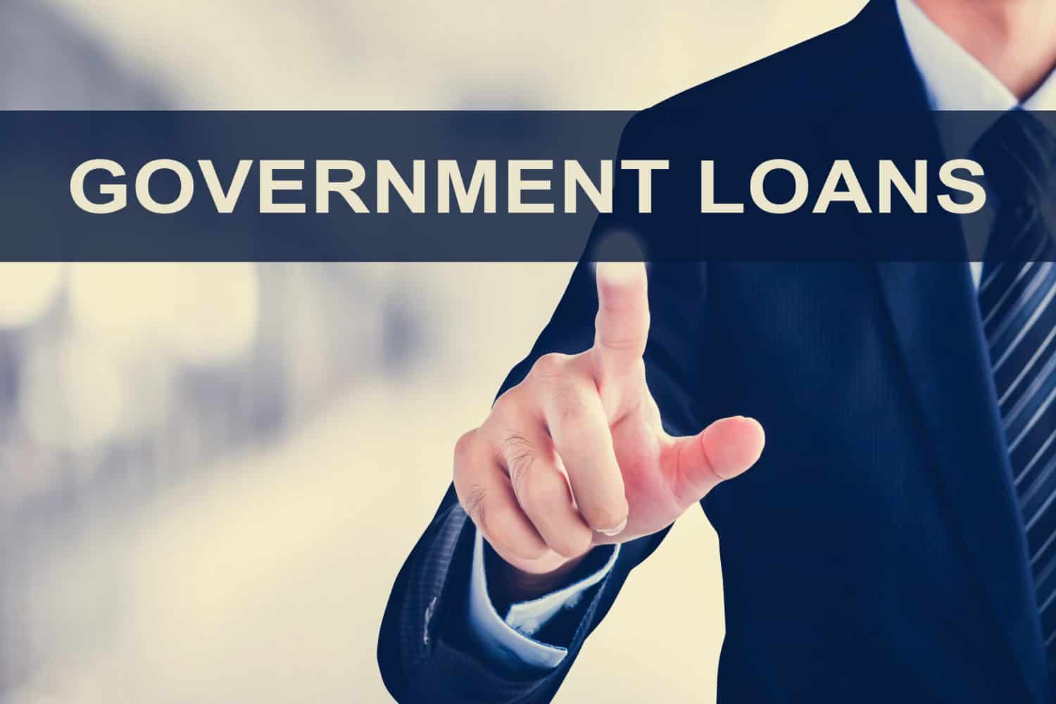 Businessman hand touching GOVERNMENT LOANS sign on virtual screen