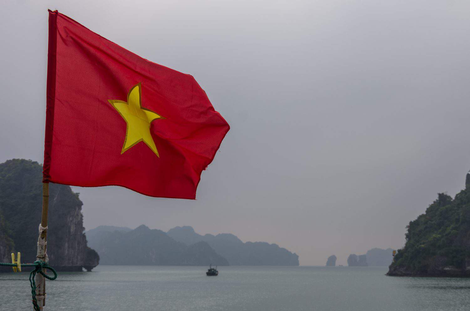 The flag of Vietnam fluttering on ship in the Halong Bay at the Gulf of Tonkin of the South China Sea, Vietnam.