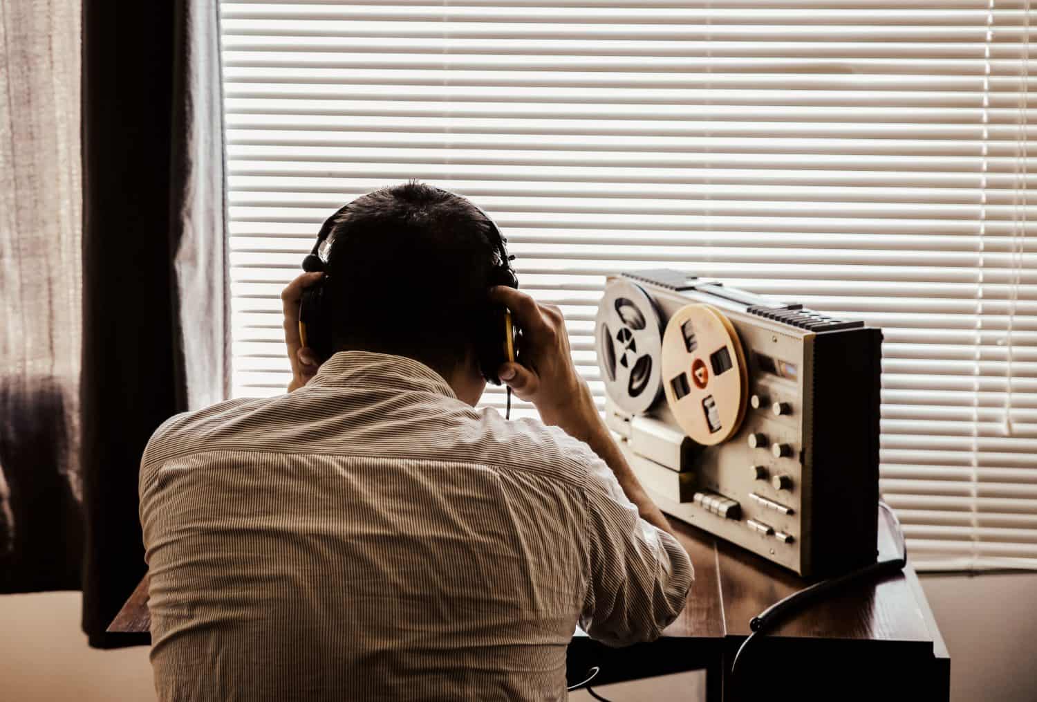 Special agent listens on the reel tape recorder. Officer wiretapping in headphones. KGB spying of conversations.