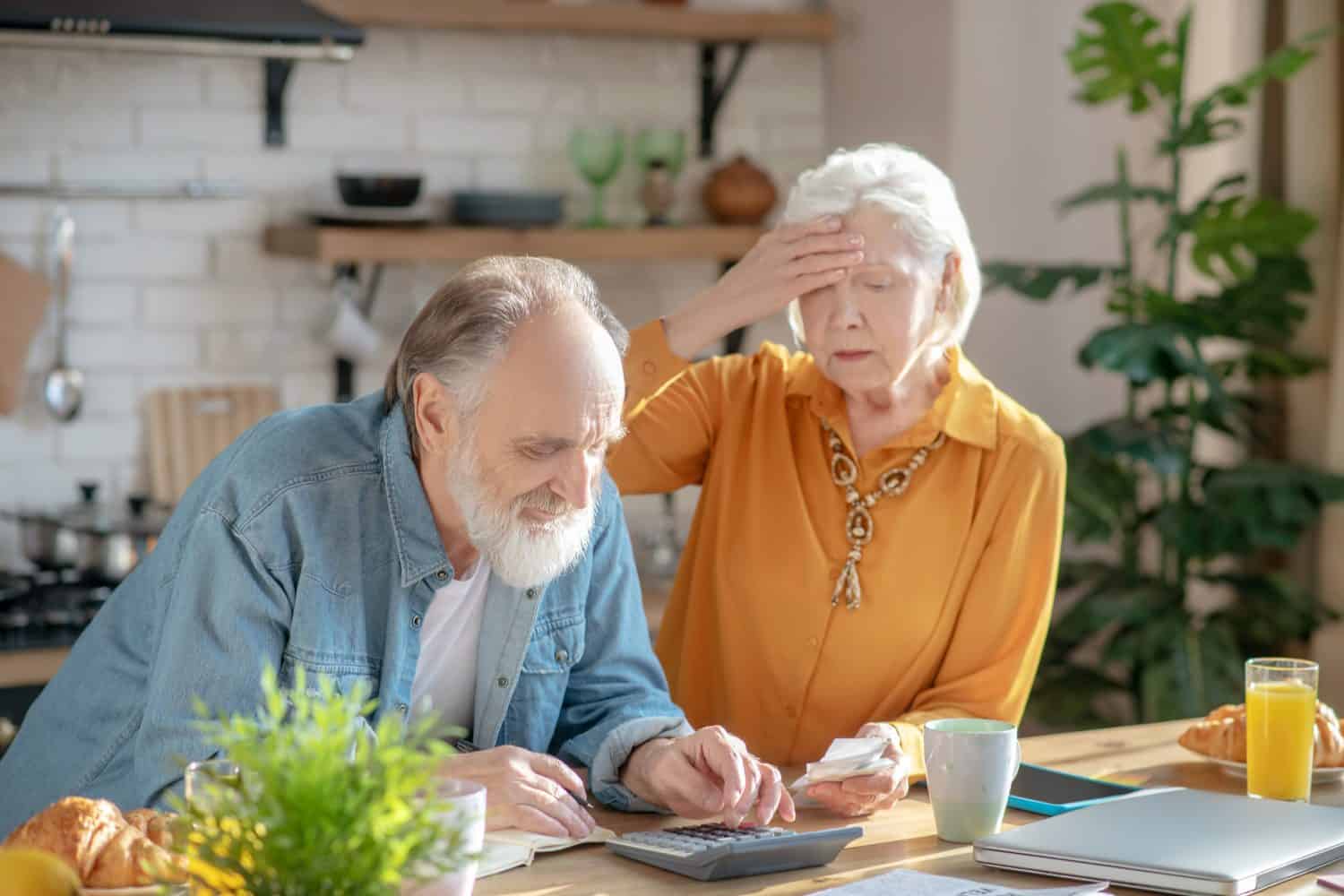 Worried about bills. Elderly married couple making calculations together and looking disturbed