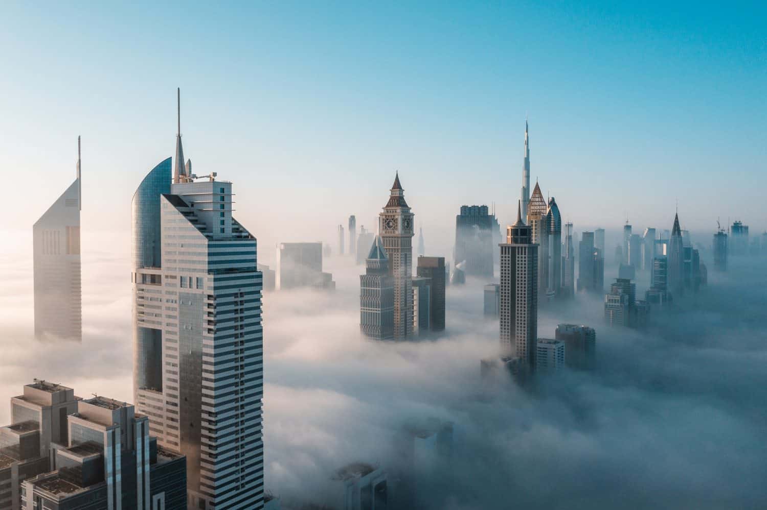 Mega tall skyscrapers of Dubai covered in early morning think fog. Rare aerial perspective.