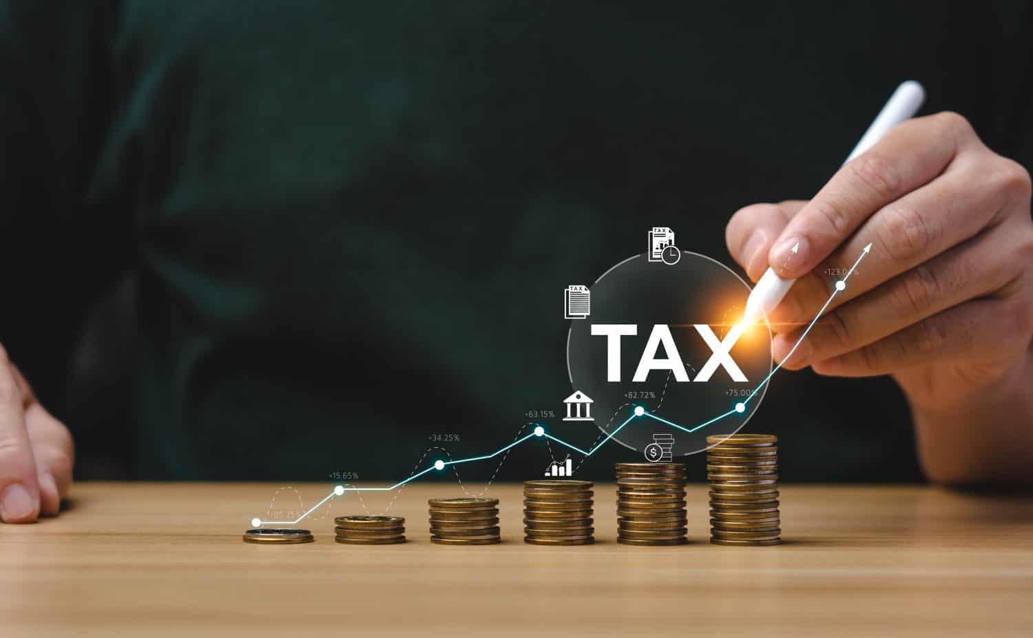 Tax deduction planning concept. Expenses, account, VAT, income tax, and property tax, pay tax. Businessman&#039;s hand and pile of coins on the table.