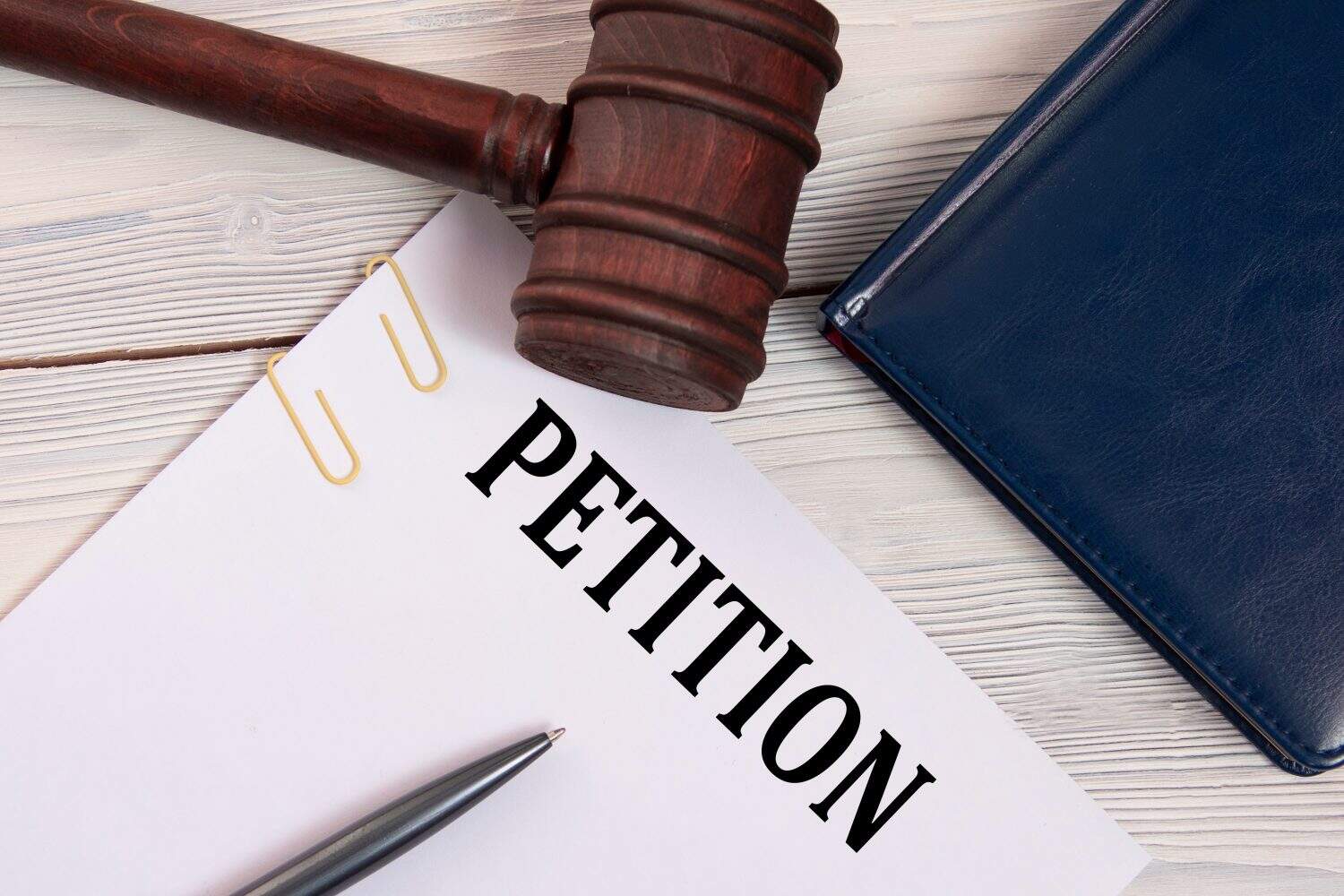 PETITION - word on a white sheet against the background of a judge's gavel, a notebook and a judge's pen. Business concept