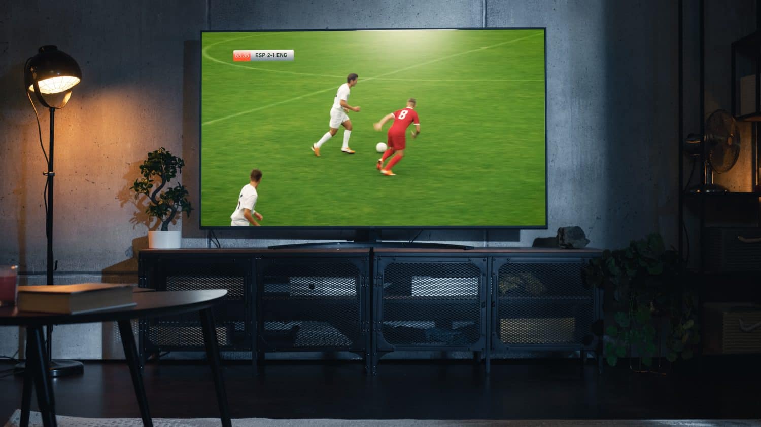 Shot of a TV with Soccer Match on Big Flat Screen Televison Set. Live Broadcast of Football World Championship Finals on Sports Channel. Cozy Game Night in Strylish Loft Apartment Living Room.