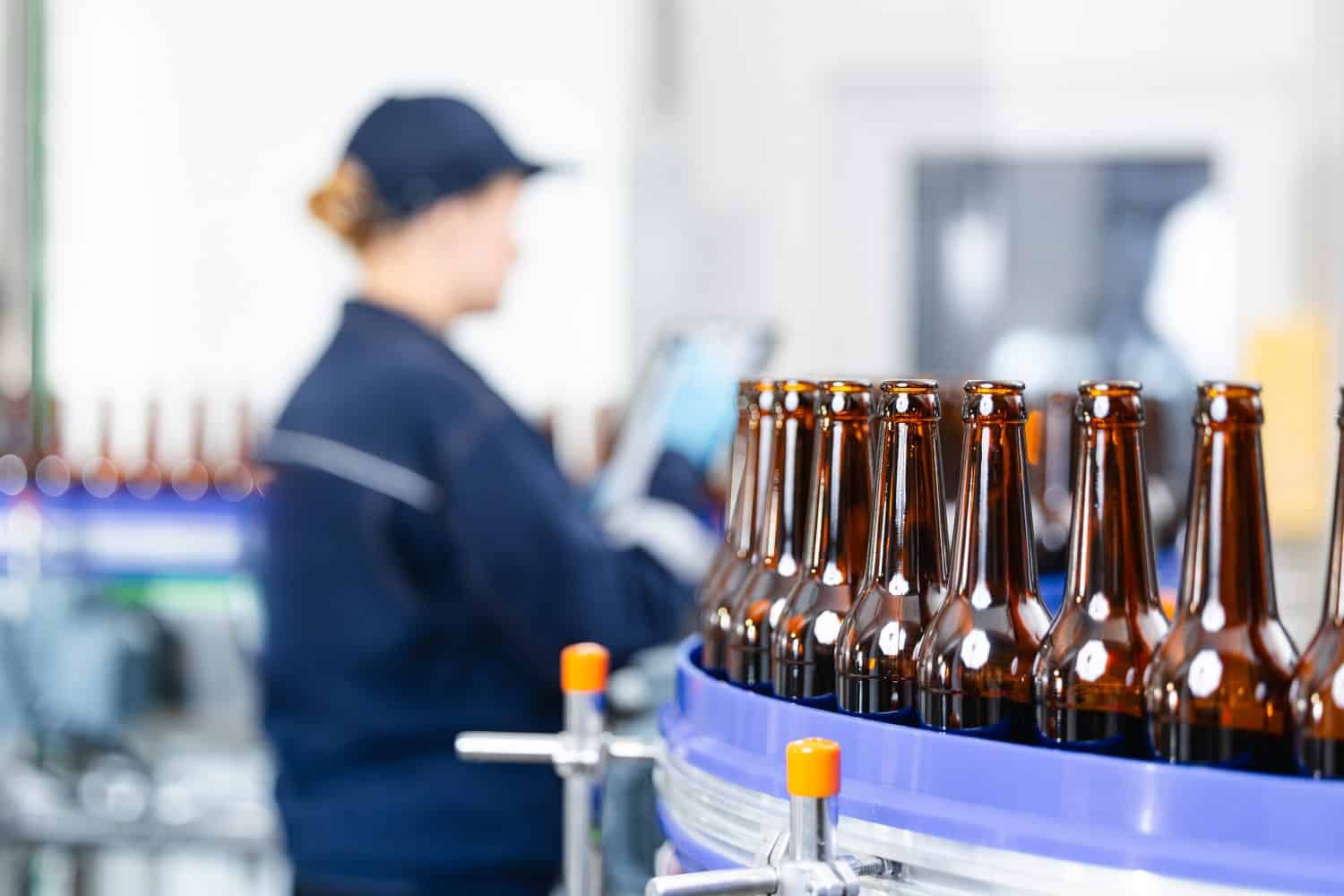 Beer production line in factory with focus on bottling process, worker control process.