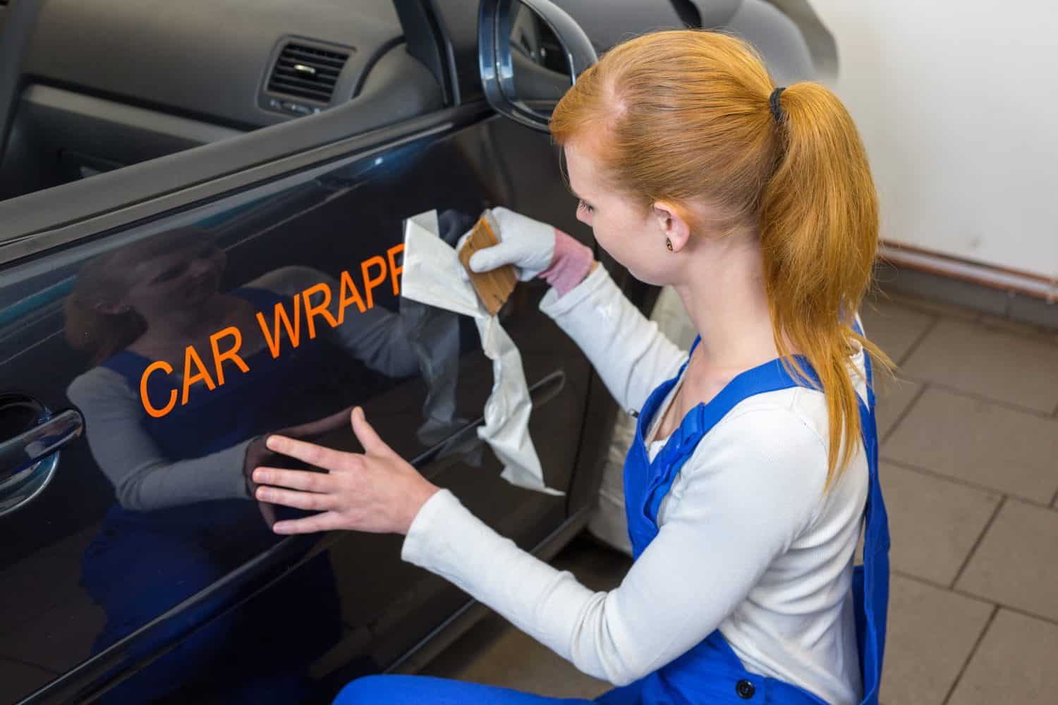 Car branding specialist puts logo with car wrapping foil or film on vehicle door