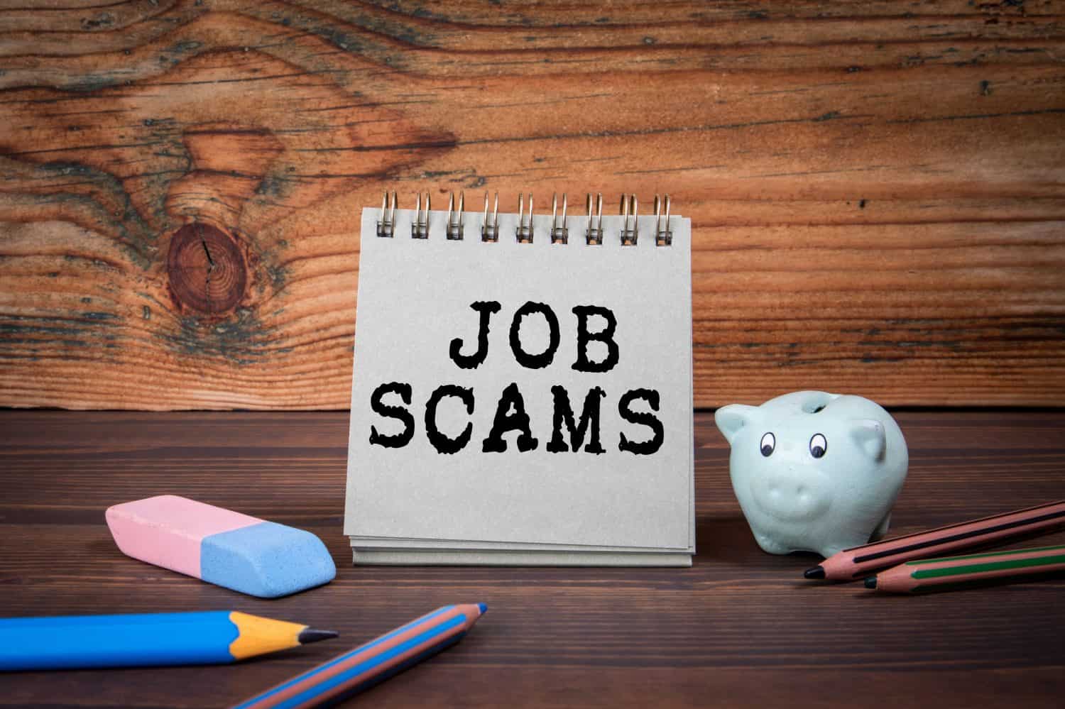 Job Scams. Cardboard notepad on wooden texture table.