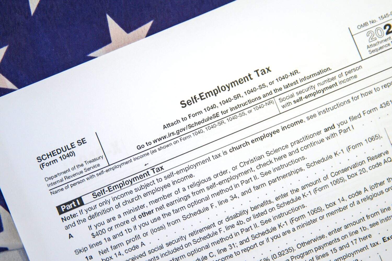 Self Employment Tax form on the American flag backdrop. 1040 for self-employment tax background