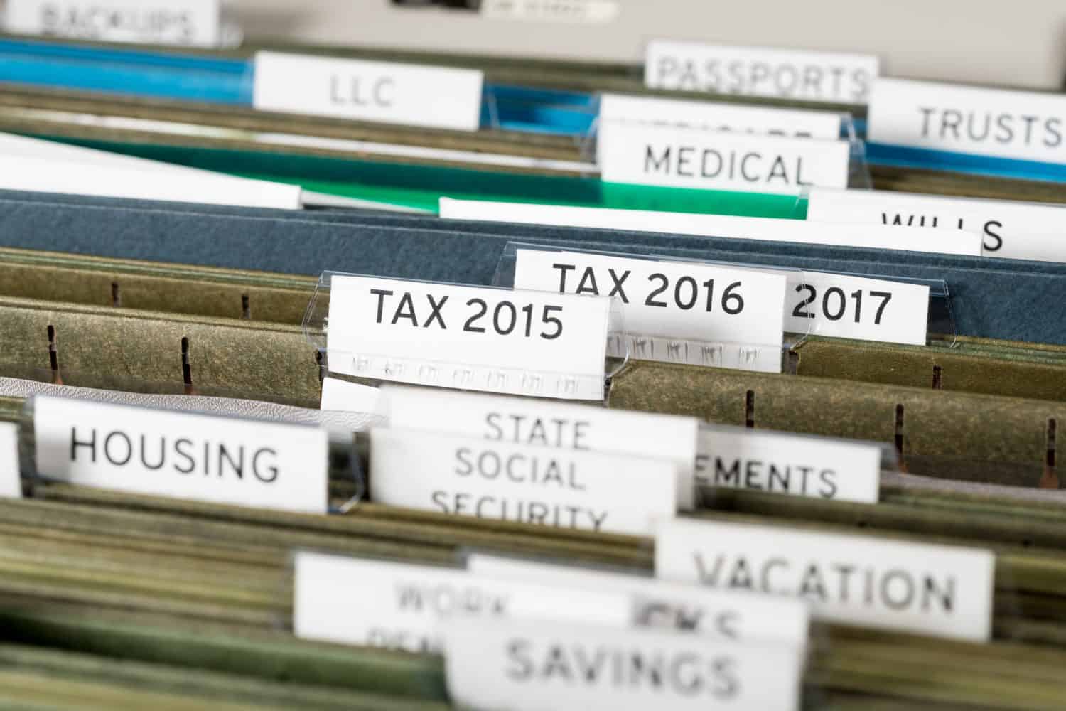 Close up of a well organized home filing system with tabs for each subject and focus on tax return papers