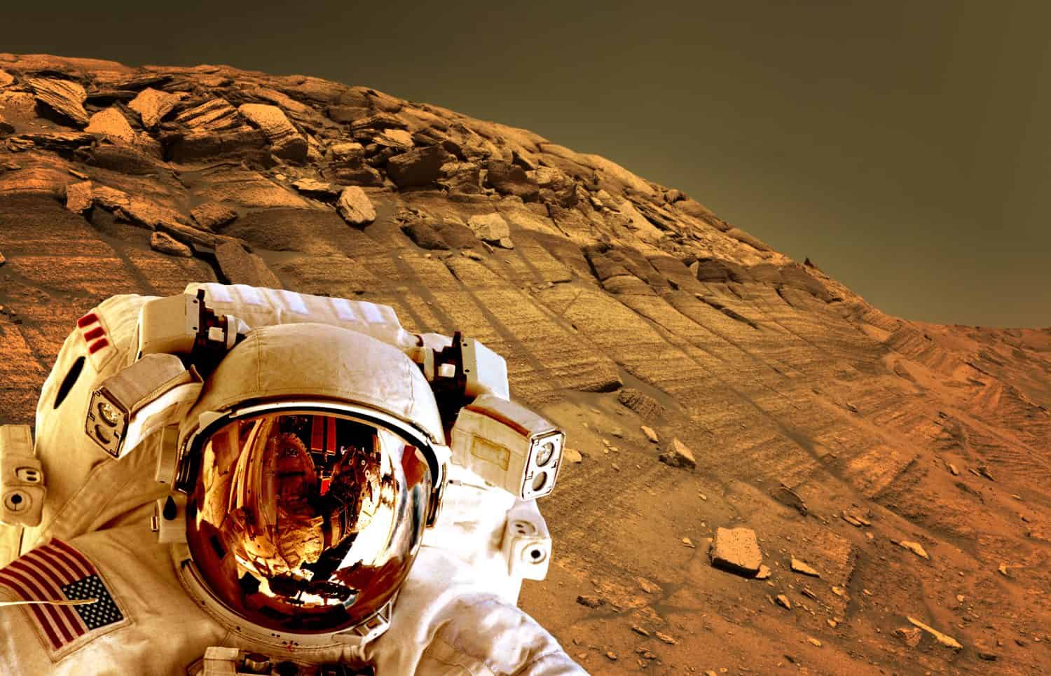 Astronaut spaceman helmet planet Mars surface martian colony space landscape. Elements of this image furnished by NASA.