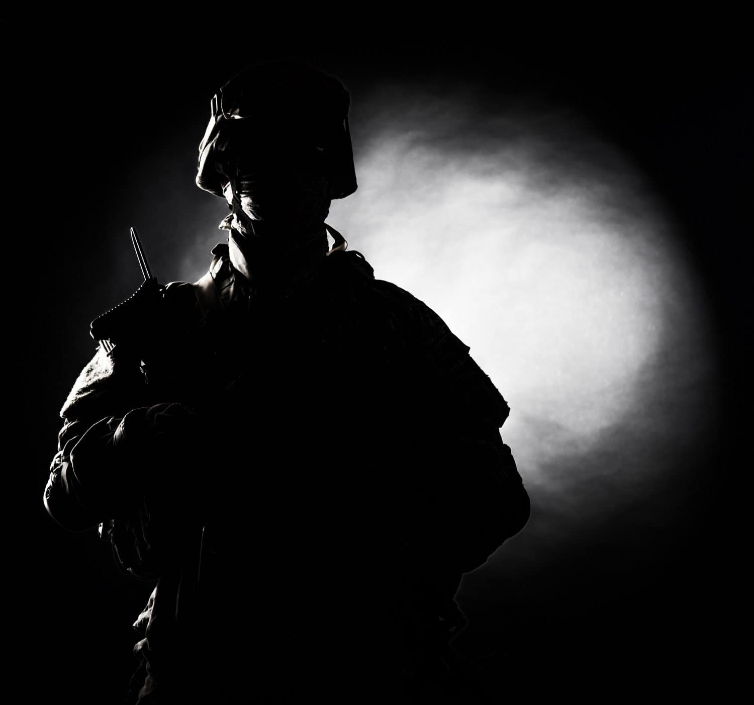 Silhouette photo of army soldier, modern combatant, military conflict participant standing in combat uniform with fiery spot on black background. Fire of war, ashes of battle, nuclear fire concept