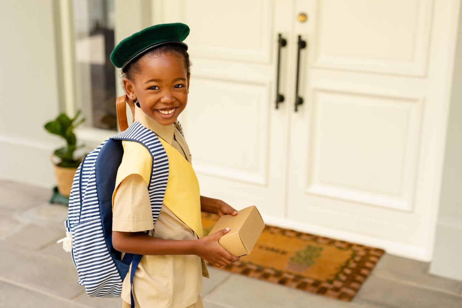 Smiling african american scout girl in uniform delivering package at home. unaltered, girl scout, childhood, courage, leadership, delivery and scouting.