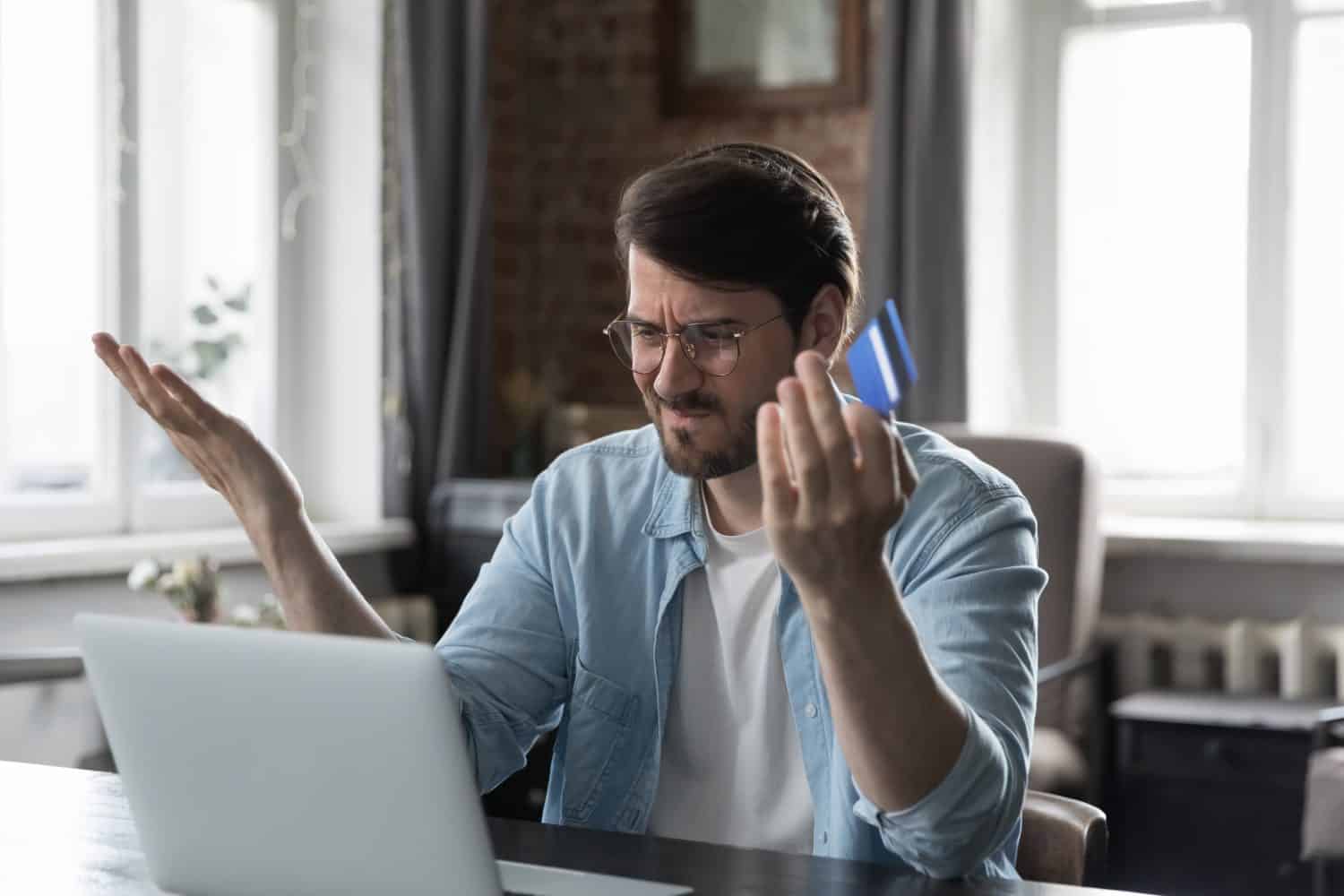 Man sit at desk with laptop use online banking service, faced with blocked credit card, financial problem, check balance feels irritated. Internet fraud, unsuccessful pay, money theft, funds overspend
