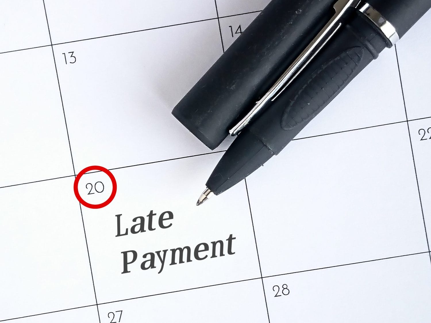 Late payment text reminder with pen on calendar. Photo concept.
