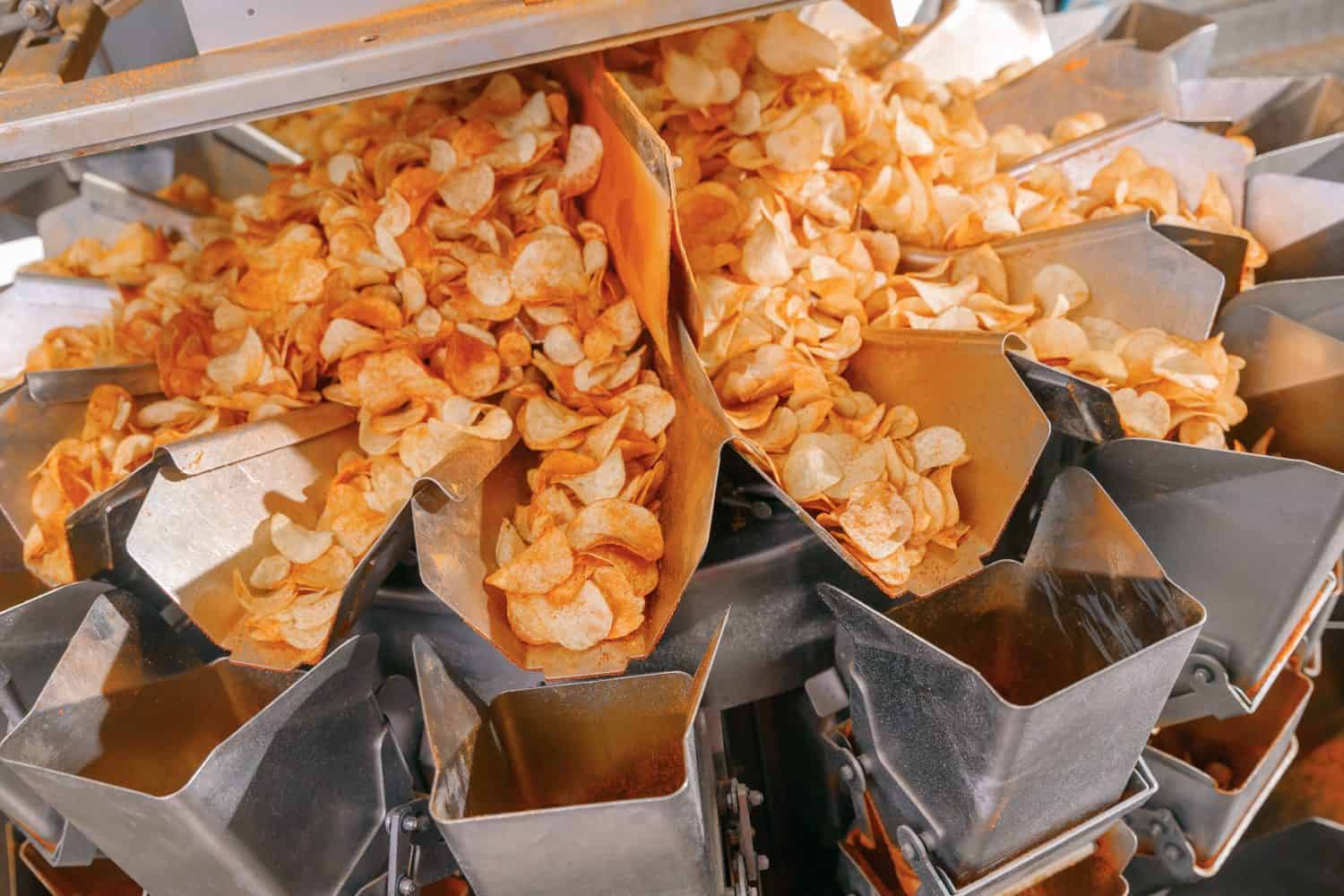 Potato chips production line at food industrial plant. Filling machines for snacks.
