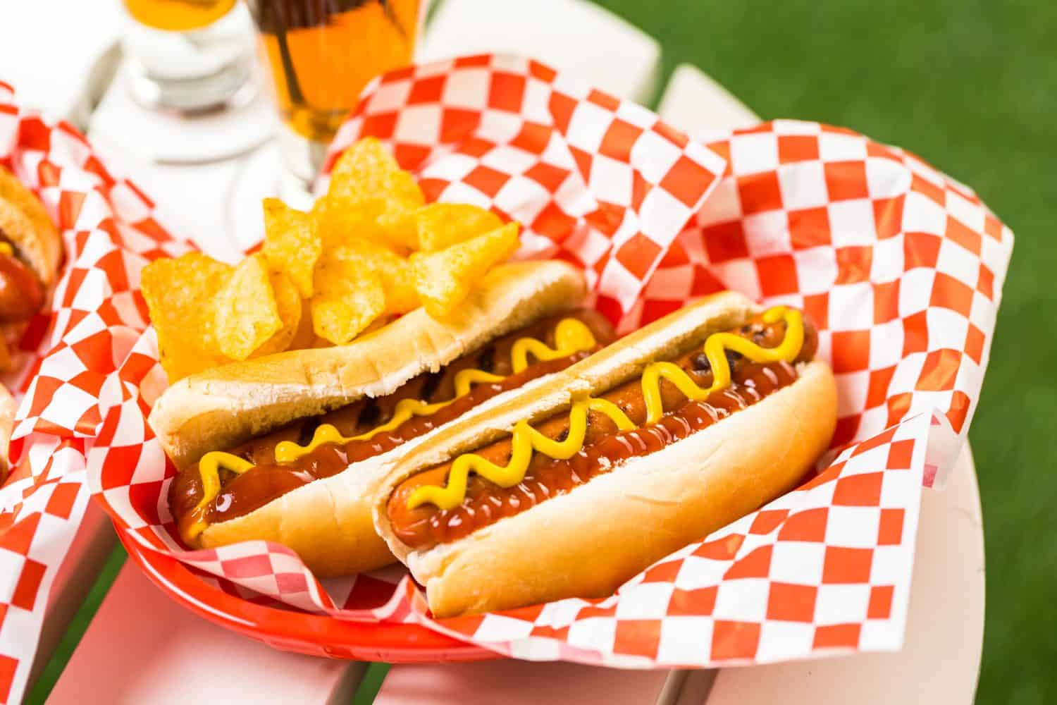Grilled hot dogs with mustard and ketchup on the table with draft beer.