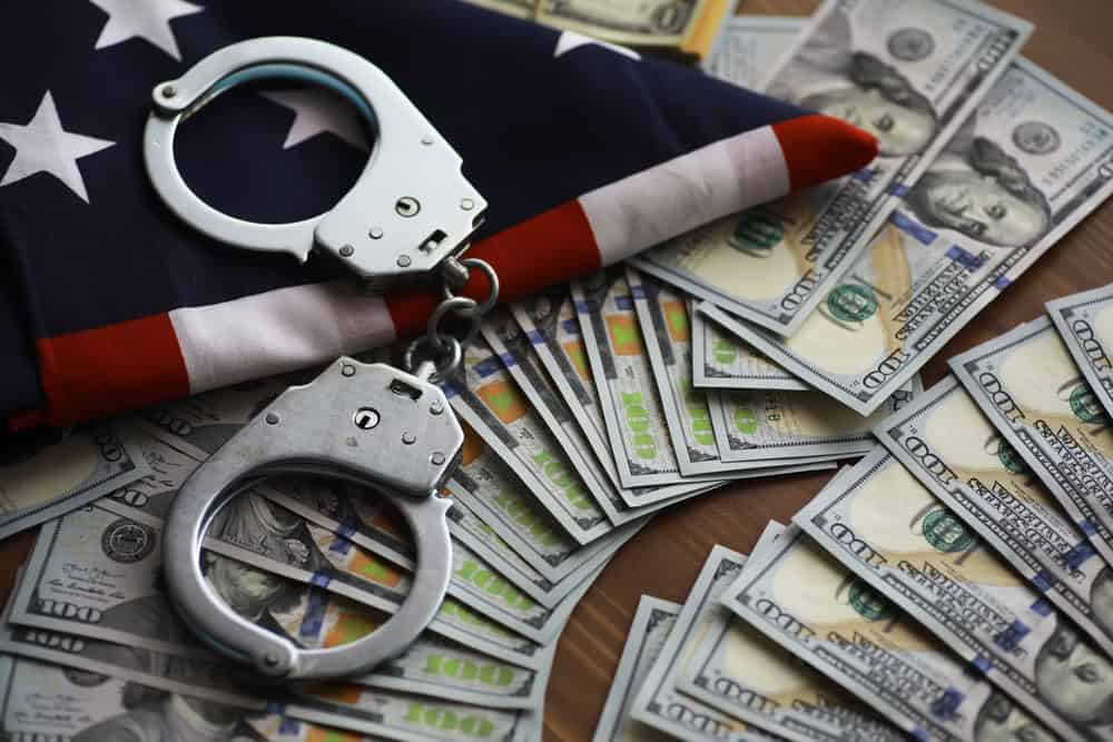American Flag and Handcuffs on Piles of U.S. Dollar Bills Representing Financial Crime and Legal Issues