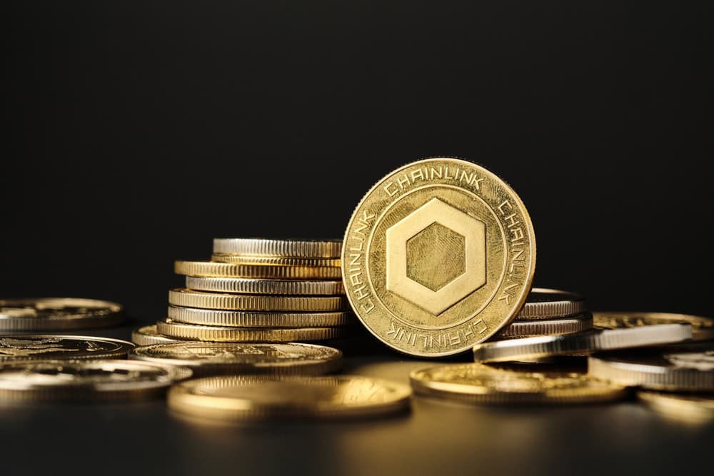 A prominent chainlink coin shines brightly among other coins in a close-up view, with a black background highlighting the gold tones.