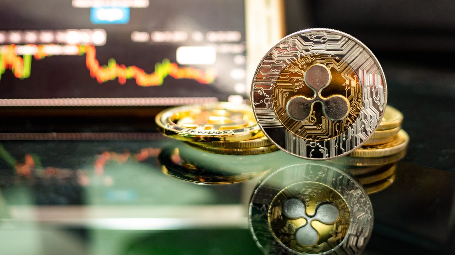 Ripple coins (XRP) Placed on a black floor with reflection and behind have graph is shown on the monitor. Concept Direction of the XRP coin.