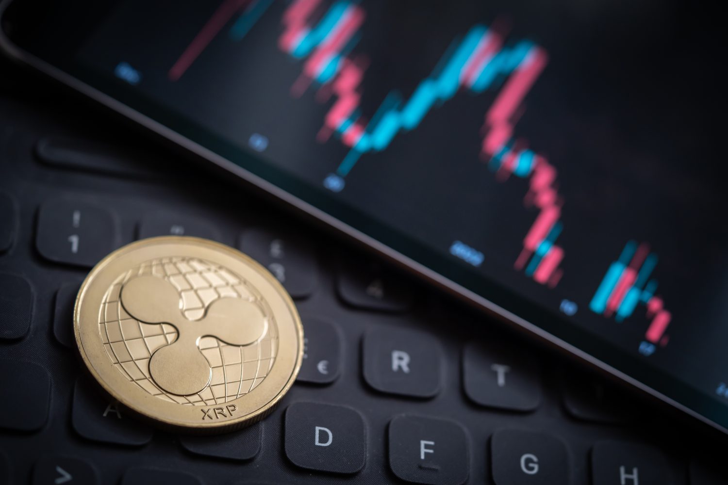 Golden Ripple (XRP) cryptocurrency coin with candle stick graph chart, laptop keyboard, and digital background.
