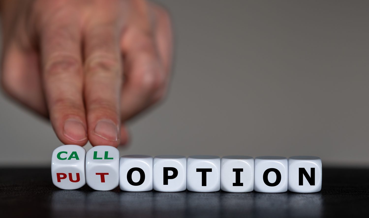 Hand turns dice and changes the expression 'put option' to 'call option'.