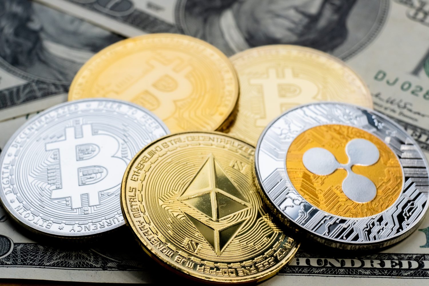 Crypto Coins Bitcoin, Ethereum and Ripple close-up on 100 American Dollars bank notes. Business cryptocurrency background.