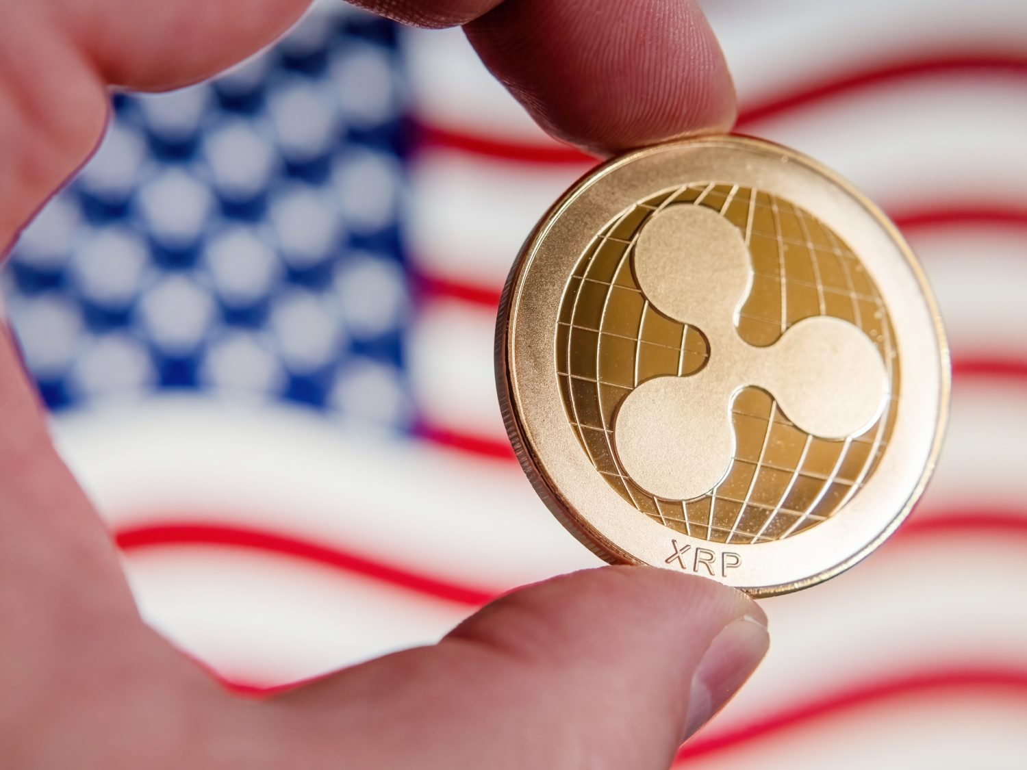 This symbolic golden XRP Ripple coin on the US flag represents the strength of cryptocurrency in the American economy