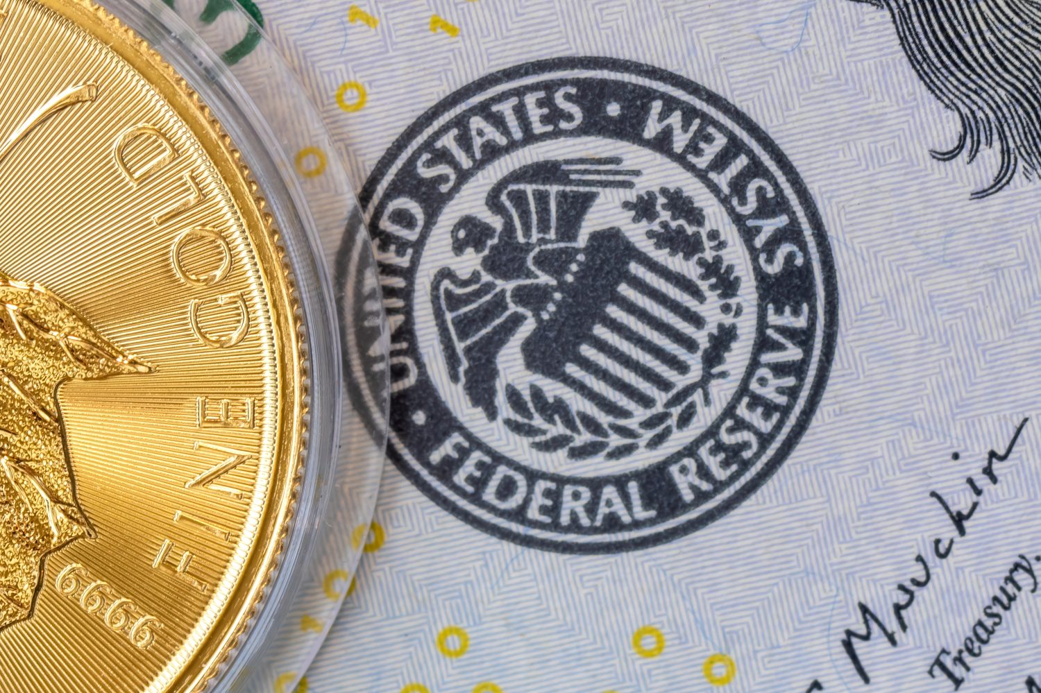 The Federal Reserve (Fed) logo on a dollar bill next to a one-ounce gold coin, symbolizing the concept of a stable currency value in relation to gold and the gold price.