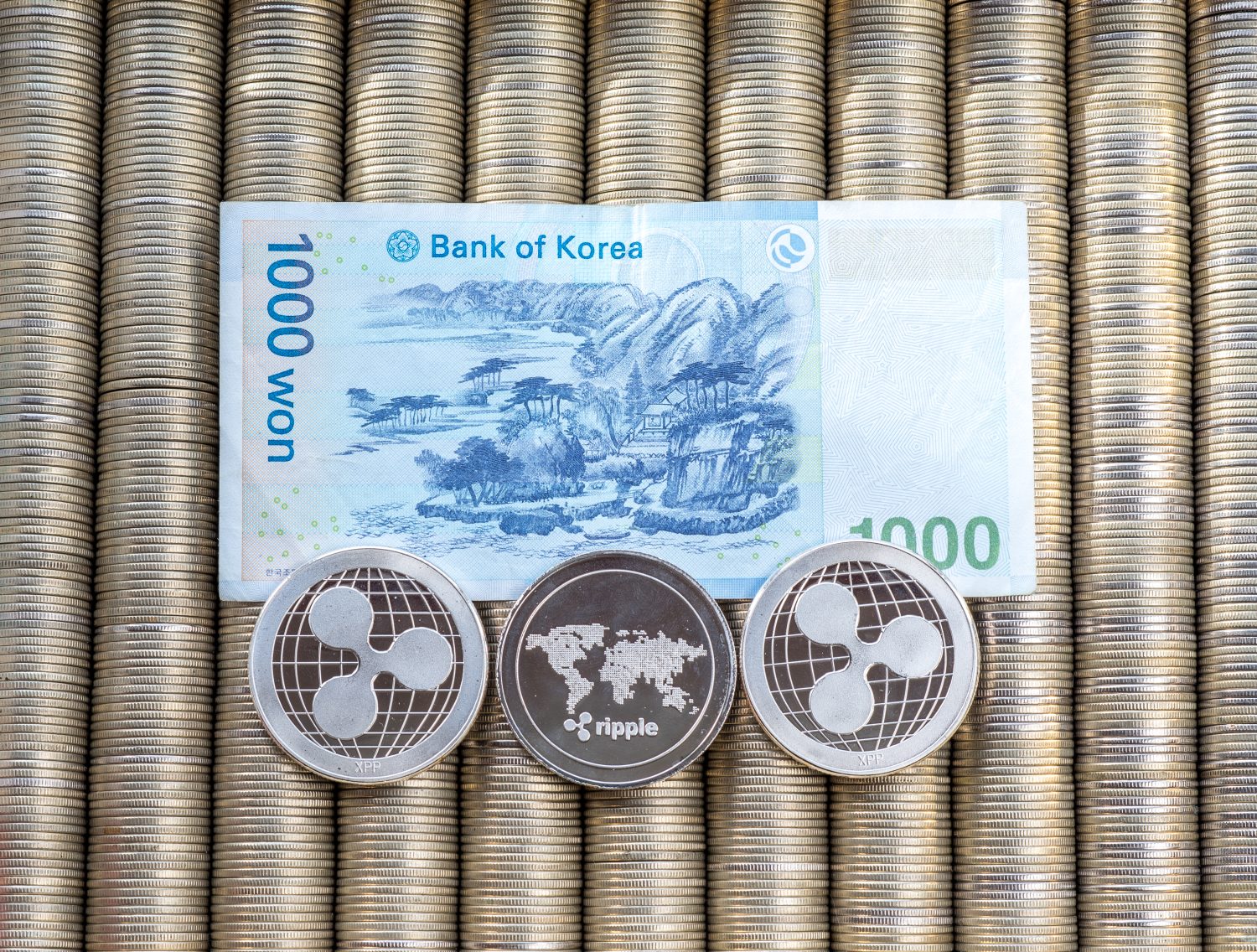 Silver crypto coins Ripple XRP, paper denominations Korean won. Metal coins are laid out in a smooth background to each other, close-up view from the top, crypto currency exchange of money.